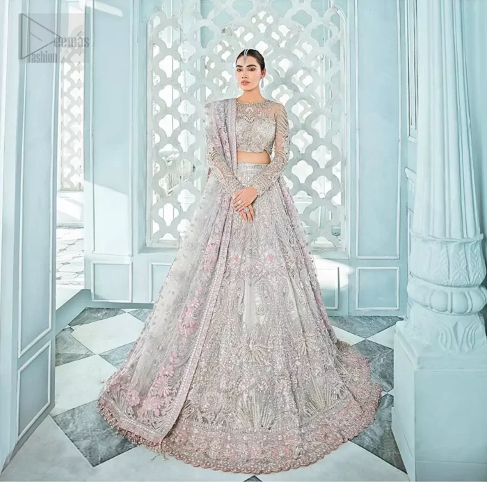 Its an unforgettable look that will effortlessly take you from day to night this festive season. Unique craftsmanship and detailed embellishments bring heavenly hued gossamer fabrics to life, creating delicate yet flamboyant pieces of art in our collection. The light gray blouse is delicately crafted with silver zardozi embellishment and finishing with scalloped sleeves and tassels. It is coordinated with lehenga which is heavily laden with sumptuous details of zardozi, applique, kora and dabka. Furthermore the lehenga is enhansed with pink applique bottom. Complete the look with light gray organza dupatta with rich embroidered floral motifs places artistically on the dupattas pallu gives a royal look.