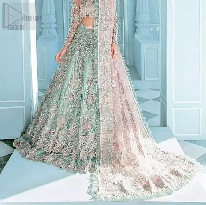 A enchanting amalgamation. This fairytale ensemble is everything that you need to impress everyone. The fusion of rich fabrics intricately designed with floral powdery hue. Precious uncut stones are threaded together with silver zardozi on pastel color palette to give it an enchantingly exquisite look. The illusion neckline blouse is laden with silver kora, dabka details and pair it up with a beautiful lehenga. The lehenga is adorned with colorful chatta patti waist belt and a captivating geometric jaal finished with scattered floral motifs and scalloped hemline. Finish the look with pink dupatta focusing on heavily embellished borders on all four sides to give it a perfect maharani look.