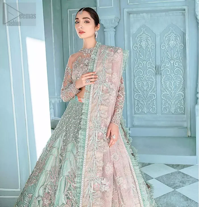 A enchanting amalgamation. This fairytale ensemble is everything that you need to impress everyone. The fusion of rich fabrics intricately designed with floral powdery hue. Precious uncut stones are threaded together with silver zardozi on pastel color palette to give it an enchantingly exquisite look. The illusion neckline blouse is laden with silver kora, dabka details and pair it up with a beautiful lehenga. The lehenga is adorned with colorful chatta patti waist belt and a captivating geometric jaal finished with scattered floral motifs and scalloped hemline. Finish the look with pink dupatta focusing on heavily embellished borders on all four sides to give it a perfect maharani look.