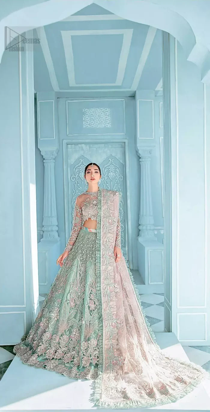 A enchanting amalgamation. This fairytale ensemble is everything that you need to impress everyone. The fusion of rich fabrics intricately designed with floral powdery hue. Precious uncut stones are threaded together with silver zardozi on pastel color palette to give it an enchantingly exquisite look. The illusion neckline blouse is laden with silver kora, dabka details and pair it up with a beautiful lehenga. The lehenga is adorned with colorful chatta patti waist belt and a captivating geometric jaal finished with scattered floral motifs and scalloped hemline. Finish the look with pink dupatta focusing on heavily embellished borders on all four sides to give it a perfect maharani look.