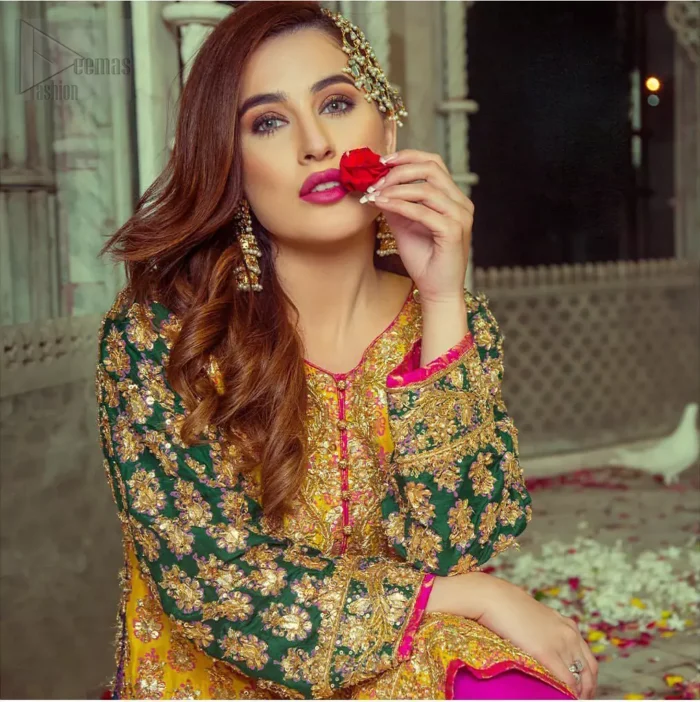 Embrace the season of festivities with this beautiful dress. This beautiful mehndi dress comes with a pink capri pants with beautiful embellished applique around the bottom and the shirt is designed with vertically worked gold lines and it finished with a thick appliqued embellished border. The shirt looks more whimsical when it comes with embellished green sleeves with golden zardozi work. Balance the look with yellow organza dupatta scattered with sequins on the ground.