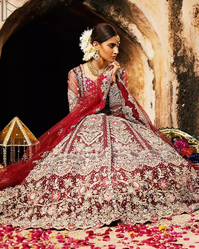 Complete your big day with the perfect dress in our selection of stunning wedding dresses. This artisanal piece is rendered in grace and timelessness. The bodice with a sweetheart neckline is adorned in richly zardozi work with fabulous sparkle. The rest of the dress is beautifully crafted with floral motifs, geometric patterns and embroidered lines along the length. Pair it up with a red lehenga emphasized with multiple colour kora, dabka, tilla and sequins work. Furthermore, the outfit is also adorned with sequins spray all over the ground. Complete the look with an artfully coordinated dupatta having embellished scalloped borders and scattered tiny floral motifs.