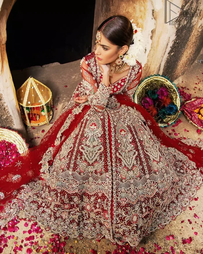 Complete your big day with the perfect dress in our selection of stunning wedding dresses. This artisanal piece is rendered in grace and timelessness. The bodice with a sweetheart neckline is adorned in richly zardozi work with fabulous sparkle. The rest of the dress is beautifully crafted with floral motifs, geometric patterns and embroidered lines along the length. Pair it up with a red lehenga emphasized with multiple colour kora, dabka, tilla and sequins work. Furthermore, the outfit is also adorned with sequins spray all over the ground. Complete the look with an artfully coordinated dupatta having embellished scalloped borders and scattered tiny floral motifs.