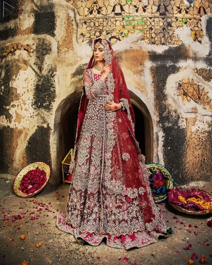 Complete your big day with the perfect dress in our selection of stunning wedding dresses. This artisanal piece is rendered in grace and timelessness. The bodice with a sweetheart neckline is adorned in richly zardozi work with fabulous sparkle. The rest of the dress is beautifully crafted with floral motifs, geometric patterns and embroidered lines along the length. Pair it up with a red lehenga emphasized with multiple colour kora, dabka, tilla and sequins work. Furthermore, the outfit is also adorned with sequins spray all over the ground. Complete the look with an artfully coordinated dupatta having embellished scalloped borders and scattered tiny floral motifs.