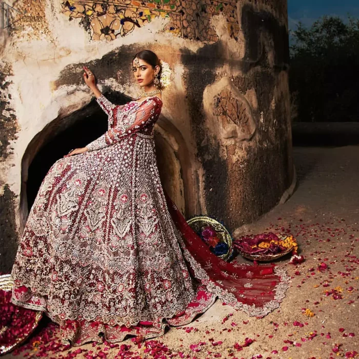 Complete your big day with the perfect dress in our selection of stunning wedding dresses. This artisanal piece is rendered in grace and timelessness. The bodice with a sweetheart neckline is adorned in richly zardozi work with fabulous sparkle. The rest of the dress is beautifully crafted with floral motifs, geometric patterns and embroidered lines along the length. Pair it up with a red lehenga emphasized with multiple colour kora, dabka, tilla and sequins work. Furthermore, the outfit is also adorned with sequins spray all over the ground. Complete the look with an artfully coordinated dupatta having embellished scalloped borders and scattered tiny floral motifs.