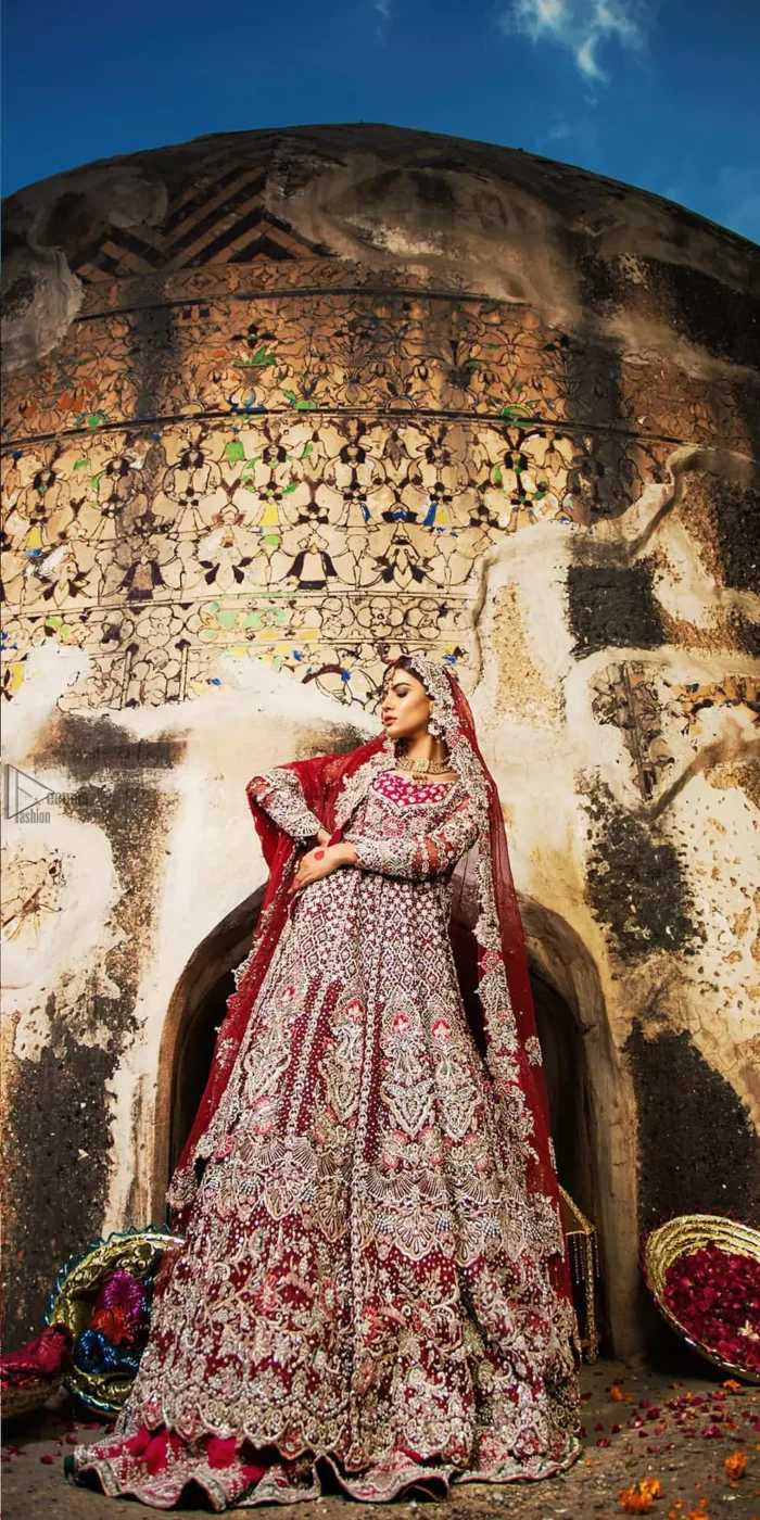 Complete your big day with the perfect dress in our selection of stunning wedding dresses. This artisanal piece is rendered in grace and timelessness. The bodice with a sweetheart neckline is adorned in richly zardozi work with fabulous sparkle. The rest of the dress is beautifully crafted with floral motifs, geometric patterns and embroidered lines along the length. Pair it up with a red lehenga emphasized with multiple colour kora, dabka, tilla and sequins work. Furthermore, the outfit is also adorned with sequins spray all over the ground. Complete the look with an artfully coordinated dupatta having embellished scalloped borders and scattered tiny floral motifs.