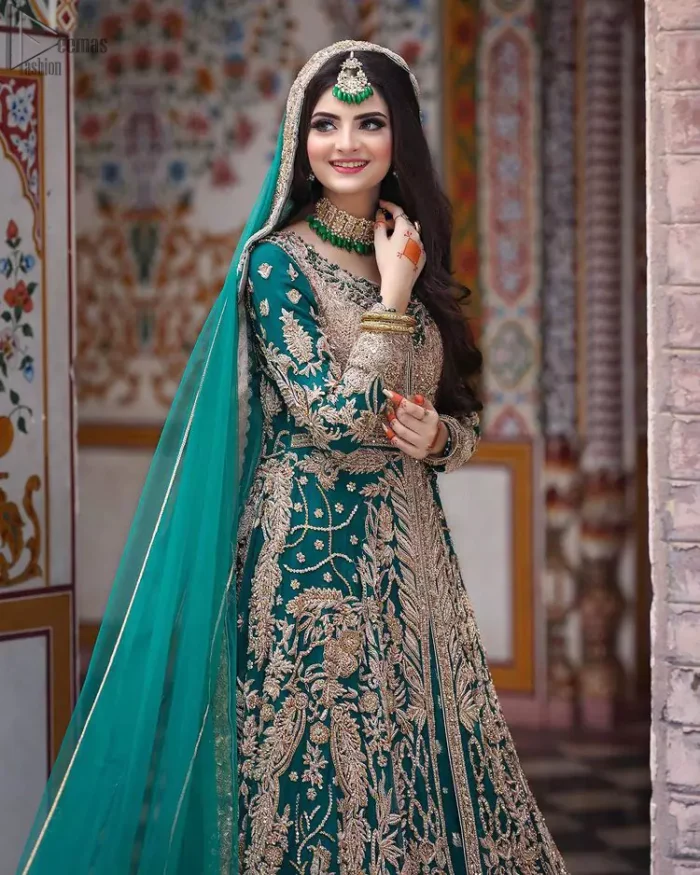 This breathtaking fit and flare wedding dress offers comfort without compromising on style. Featuring beautiful handwork, this outfit has a delicate arrangement of hand-embellished floral patterns with champagne zardozi work along the length. Refined craftsmanship is at its best with a hand embellished belt clenched elegantly at the waistline. It comes with a sea-green lehenga adorned with tiny motifs spray all over the ground and exaggerated with embroidered lace bottom. This outfit is paired up with an organza dupatta with embroidered border to give it a perfect ending.