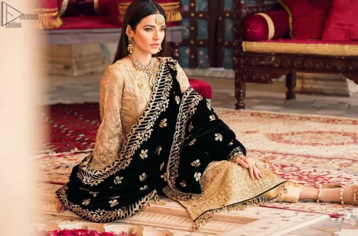 The beige pure organza shirt has been appliqued with black velvet on cuffs and on the hemline. This straight shirt comes with pure banarsi jamawar cigarette Pants. Dupatta is like a shawl in velvet a perfect combination for Nikah n Engagement.