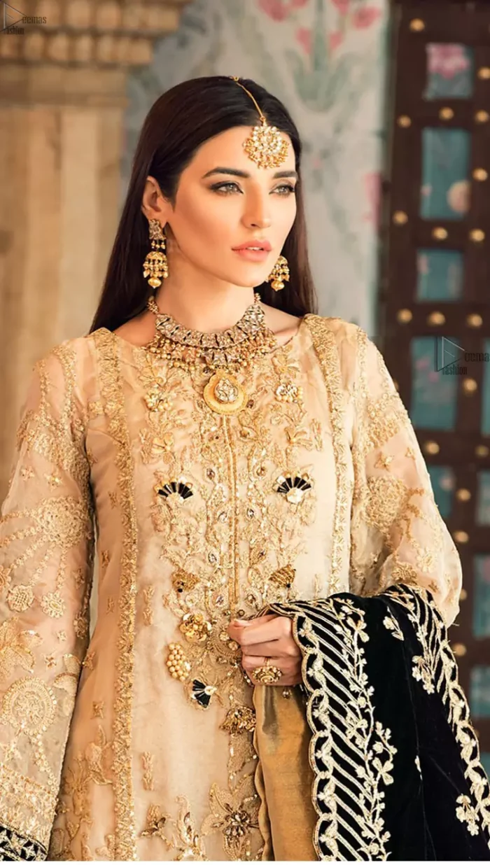 The beige pure organza shirt has been appliqued with black velvet on cuffs and on the hemline. This straight shirt comes with pure banarsi jamawar cigarette Pants. Dupatta is like a shawl in velvet a perfect combination for Nikah n Engagement.