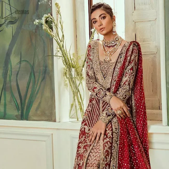 Chic, sleek and undeniably romantic, this beautiful deep red gown might just be the one for you. With pure fabric heavily laden with zardozi and the perfect blend of traditional flamboyance and modern elegance in design, you need to look no further for the perfect look for your special day. The bodice is heavily decorated with zardozi work, the rest of the gown is enriched with floral bootis and finished with the thick embellished bottom. Complete the look with an artfully coordinated lehenga which is ornamented with geometric patterns and captivating back trail design with traditional intricate embroidery. The outfit is coordinated with an organza dupatta finessed with embroidered borders.