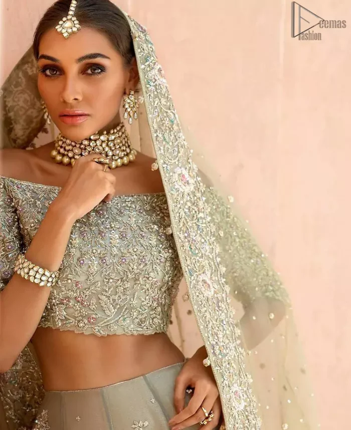 When extreme beauty is your identity, the Olive Green Off Shoulder Blouse Lehenga makes sure it boosts your gorgeousness with its much more attractive elegance. This paragon of exquisiteness is designed with three-quarter sleeves, making sure it meticulously matches its objective. The silver and golden embroidery serve as the cherry on top, while the stunning floral motifs do not fail to catch all admiring eyes on the finest details of adornment on the dress. Finest organza as always is the prime choice for an attire so meritorious and the concluding marvellous net dupatta prepares this laudable dress to brighten up your Walima ceremony.
