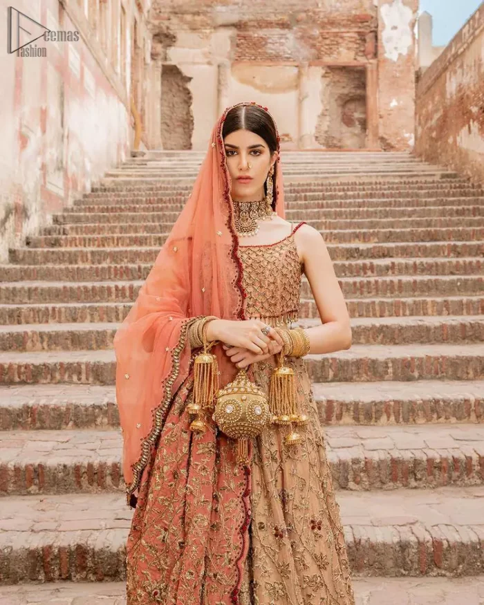 Crafted with love. This beautiful bride is a vision of impeccable grace and elegance in a divinely crafted bridal couture, with the exquisite embroideries that add the royal touch to the outfit. This off-shoulder blouse is meticulously crafted with zardozi work in the shades of golden and antique, finished the blouse with dangling tassels. The lehenga is emphasized with hand embellished floral embroidery with kora, dabka, tilla, sequins and beads all over. The look is complete when it gets paired up with an organza dupatta having scalloped finishing along the length and floral jaal on both sides of pallu.