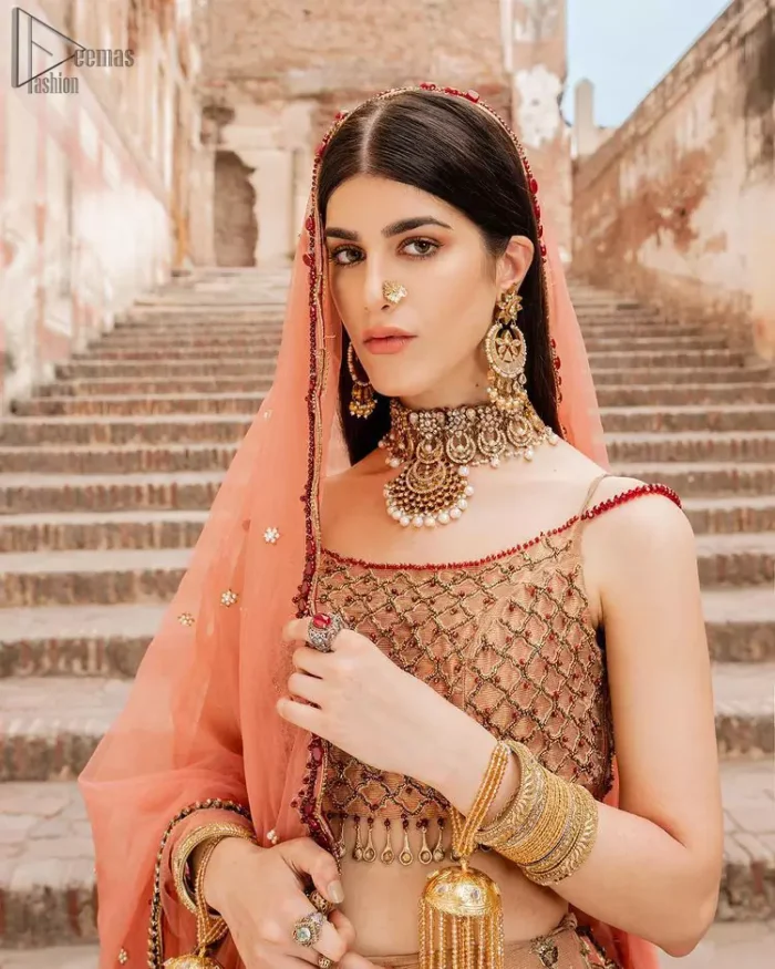 Crafted with love. This beautiful bride is a vision of impeccable grace and elegance in a divinely crafted bridal couture, with the exquisite embroideries that add the royal touch to the outfit. This off-shoulder blouse is meticulously crafted with zardozi work in the shades of golden and antique, finished the blouse with dangling tassels. The lehenga is emphasized with hand embellished floral embroidery with kora, dabka, tilla, sequins and beads all over. The look is complete when it gets paired up with an organza dupatta having scalloped finishing along the length and floral jaal on both sides of pallu.