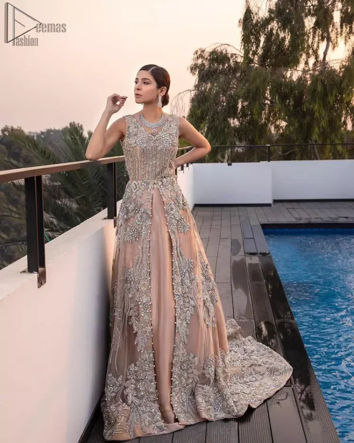 Some brides definitely shine bright by stepping out of the classic box and jumping into pastel hues for their big day. The front open back train dreamy maxi is adorned with an embellished bodice and floral booties all over the body giving a perfect ending to this outfit. The embroidery is done in the shade of silver and gold. Furthermore, the back train is emphasized with a large central motif and thick embellished borders. Coordinated with matching net lehenga and tea rose dupatta having a four-sided scalloped border.