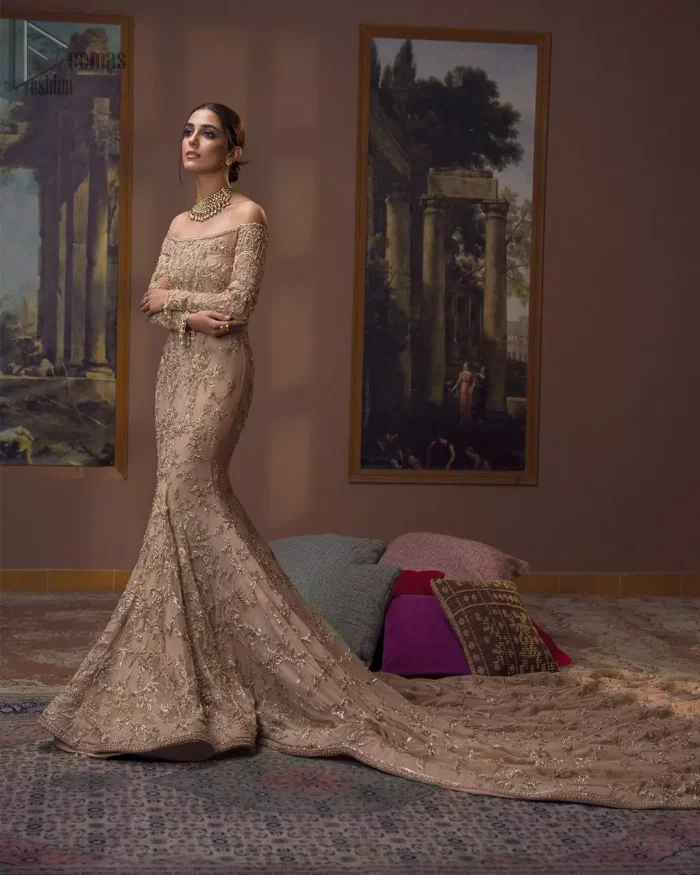 Take a step towards refreshing your wardrobe with our fawn off-shoulder back train mermaid gown. The outfit is perfected with loaded golden and silver embroidery, elevated by vibrant floral motifs and adorned in a fawn embellished with golden work detailing around the strapless neckline. All over, this undeniably elegant attire will elevate your style. Feel the dreamy vibes with this heavenly combination of fawn off-shoulder back train mermaid gown and cigarette pants adorned with floral embroidery, followed by a graceful net dupatta. Making your evening parties more beautiful.