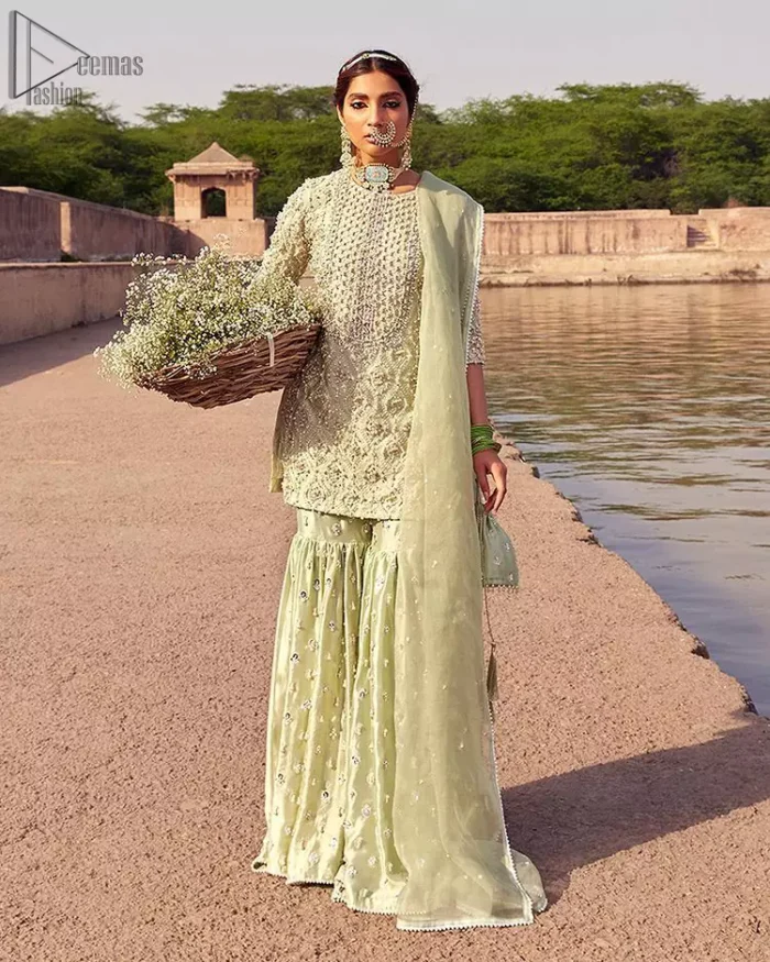 Glow up an evening formal event with a Light Parrot Green Gharara Shirt, a beautiful three-quartered sleeves shirt designed with the most accurate round neckline to make you appear the star of the night. But a star as beautiful as you need to sparkle bright, which is why the dress is adorned with an outstanding work of silver and gold embroidery and ornamented with glittering pearls. This beautiful dress is designed in a matching embellishment with criss-cross patterns to help you dress up precisely. Finally, an organza dupatta concludes your magical gorgeousness.