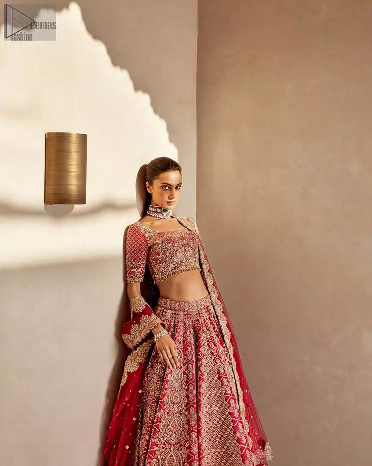 It's all about looking stunning with a gorgeous Red Lehenga Blouse on your big day. Made with pure organza, this beautiful red dress is designed with trendy half sleeves, following a blouse choli styled exquisitely with a criss-cross pattern on sleeves. A boat-shaped neckline makes your beauty bones prominent while a marvellous touch of silver and golden embroidery, in addition to a few charming tassels, contributes to the magnificence of the dress. This highly appealing attire is surely going to get you a lot of praise on your Reception day.