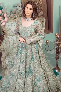 This style-savvy bride totally pulled off our classic bridal wear with unmatchable grace-giving major bridal goals. Featuring beautiful handwork, this outfit has a delicate arrangement of hand-embellished floral patterns with pearls and crystals along the length. Refined craftsmanship is at its best with hand embellished zardozi work elegantly all over the outfit. Frilled on the bottom of the maxi makes the outfit look like nothing but a dream. This outfit is paired with an organza dupatta with embroidered border and raw silk churidar pajama, making it a statement piece.