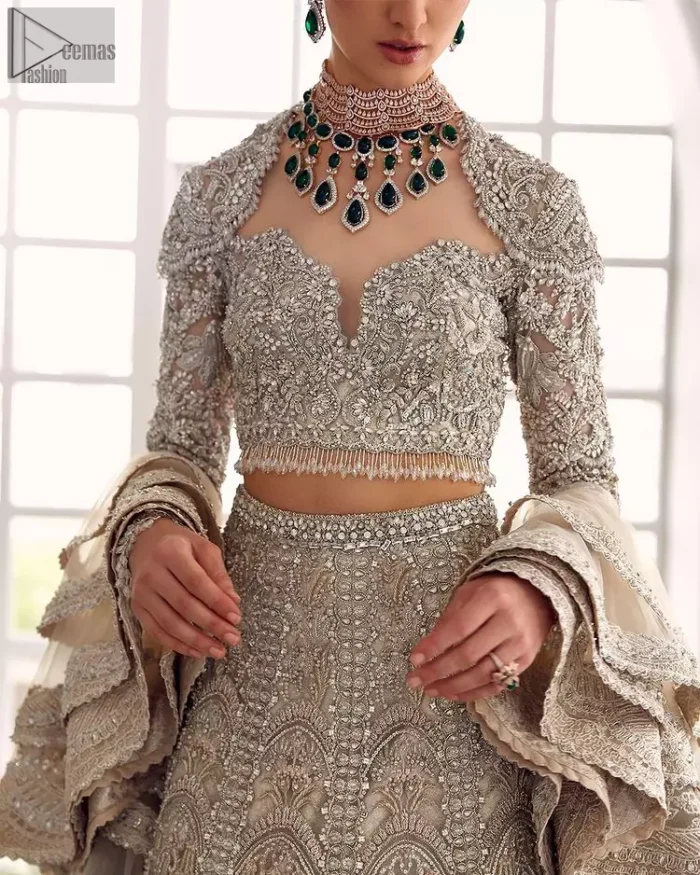 Your wedding day becomes more memorable when the guests are stunned by your majestic beauty and the perfect arrangements that are made. The Cream Lehenga Blouse is designed with such dexterity as to make you one gorgeous-looking bride on your big day. The dress code demands a full-sleeved blouse with a unique sweetheart neckline. Its exquisite fawn color is meritoriously adorned with superb silver embroidery and stylish tassels, which are indeed the most graceful works of matching embellishment. When it comes to the definition of elegance, the purest organza is specifically reserved for the creation of such marvelous attire. Followed by a beautiful dupatta and a lehenga, this charming bridal wear will make your Walima or Nikkah a heavenly day.