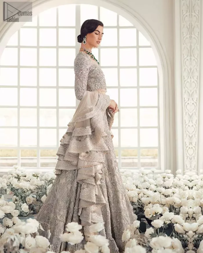 Your wedding day becomes more memorable when the guests are stunned by your majestic beauty and the perfect arrangements that are made. The Cream Lehenga Blouse is designed with such dexterity as to make you one gorgeous-looking bride on your big day. The dress code demands a full-sleeved blouse with a unique sweetheart neckline. Its exquisite fawn color is meritoriously adorned with superb silver embroidery and stylish tassels, which are indeed the most graceful works of matching embellishment. When it comes to the definition of elegance, the purest organza is specifically reserved for the creation of such marvelous attire. Followed by a beautiful dupatta and a lehenga, this charming bridal wear will make your Walima or Nikkah a heavenly day.