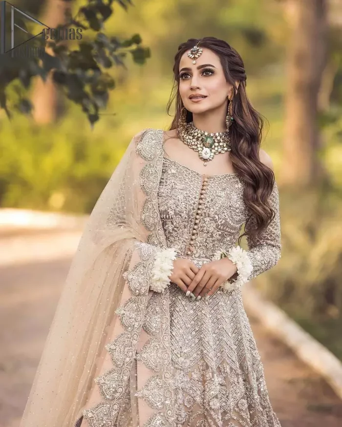 If you believed in mythical stories, shared all your secrets with glorious fairies and want to look like that mythical fairy on your reception then this Beige article is for you. This off-shoulder maxi is beautifully embellished with kora, dabka, tilla, sequins and pearls work, style up with remarkable full sleeves. Introducing this with a ruffled lehenga that looks super stunning and priceless. Followed with a net dupatta that is prominent with hand embellished borders and sequins spray all over that enhances the beauty of the outfit and give you a mythical fairy look as well.