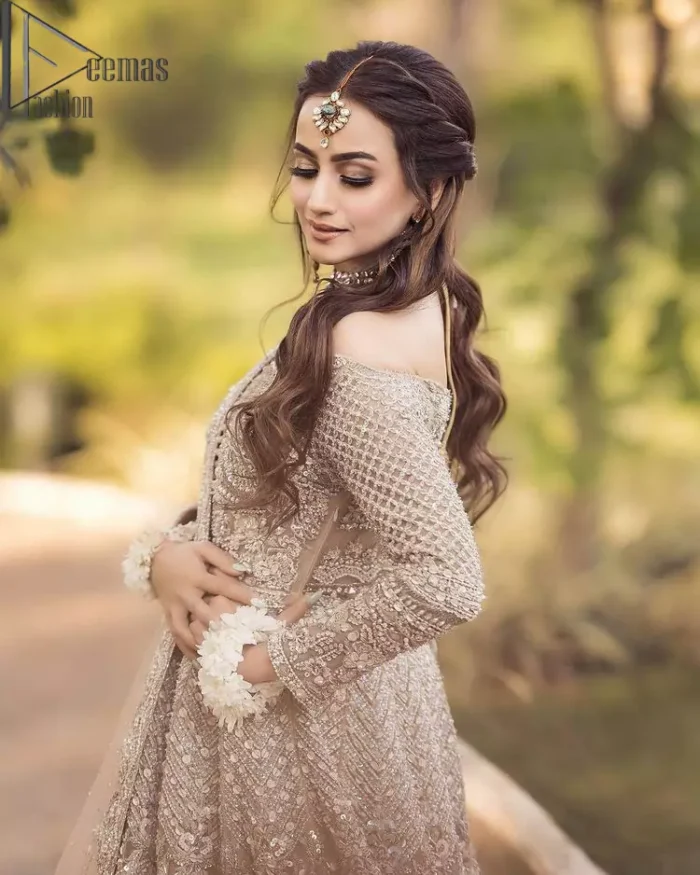 If you believed in mythical stories, shared all your secrets with glorious fairies and want to look like that mythical fairy on your reception then this Beige article is for you. This off-shoulder maxi is beautifully embellished with kora, dabka, tilla, sequins and pearls work, style up with remarkable full sleeves. Introducing this with a ruffled lehenga that looks super stunning and priceless. Followed with a net dupatta that is prominent with hand embellished borders and sequins spray all over that enhances the beauty of the outfit and give you a mythical fairy look as well.