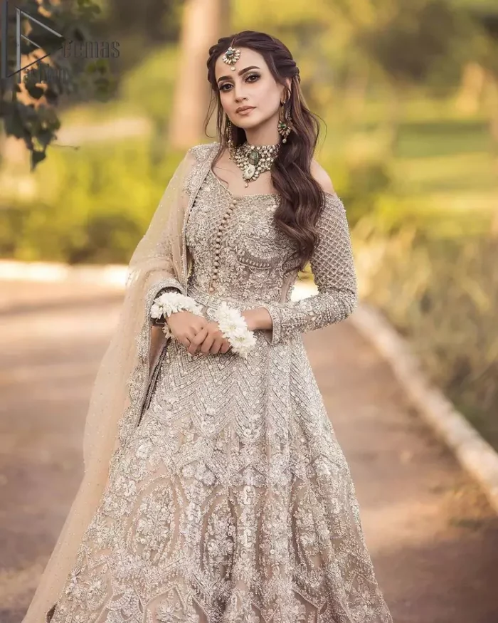 If you believed in mythical stories, shared all your secrets with glorious fairies and want to look like that mythical fairy on your reception then this Beige article is for you. This off-shoulder maxi is beautifully embellished with kora, dabka, tilla, sequins and pearls work, style up with remarkable full sleeves. Introducing this with a ruffled lehenga that looks super stunning and priceless. Followed with a net dupatta that is prominent with hand embellished borders and sequins spray all over that enhances the beauty of the outfit and give you a mythical fairy look as well.