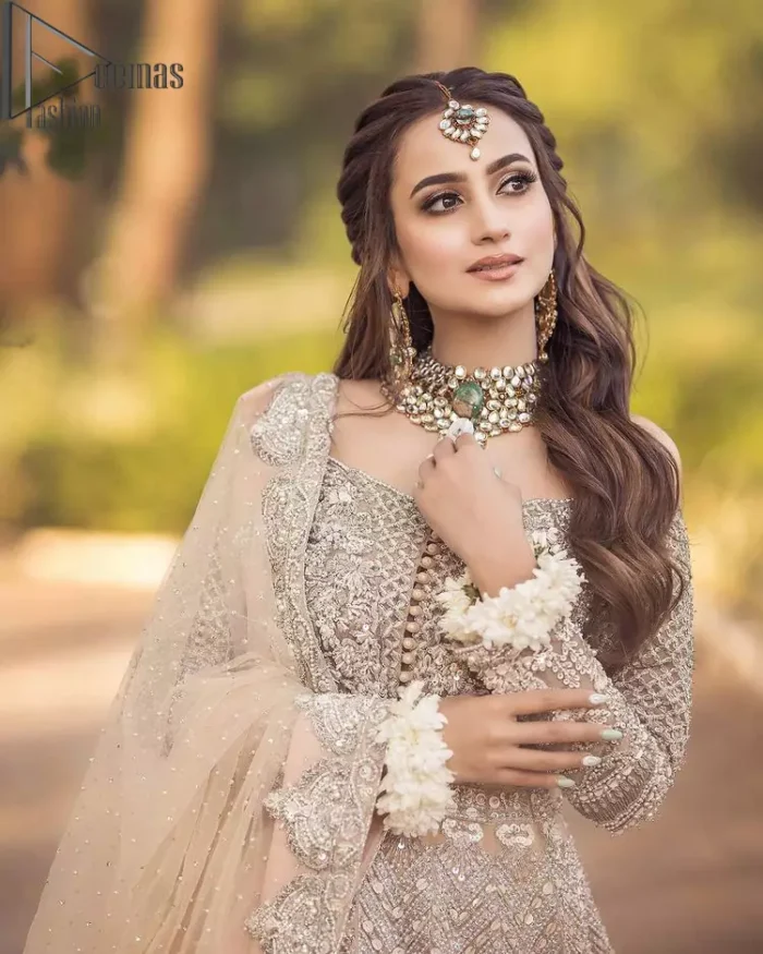 If you believed in mythical stories, shared all your secrets with glorious fairies and want to look like that mythical fairy on your reception then this Beige article is for you. This off-shoulder maxi is beautifully embellished with kora, dabka, tilla, sequins and pearls work, style up with remarkable full sleeves. Introducing this with a ruffled lehenga that looks super stunning and priceless. Followed with a net dupatta that is prominent with hand embellished borders and sequins spray all over that enhances the beauty of the outfit and give you a mythical fairy look as well.