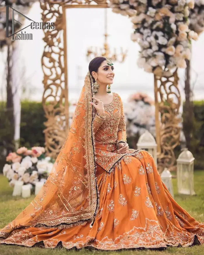Time to treat yourself with an orange article of Deemas Fashion. This orange heartiest mealtime article will twirl your heart.  Prettify your Mehndi look with this orange short shirt that is embellished with tilla, kora and dabka work. Its rounded neckline with full sleeves gives you a genuine feeling of a bride. It is synchronized with flayer orange sharara that has an embellished border and spray of tiny floral motifs that gives a super aesthetic look to this dress. Finish this look with a net dupatta that has four sides embellished border and Kiran work.