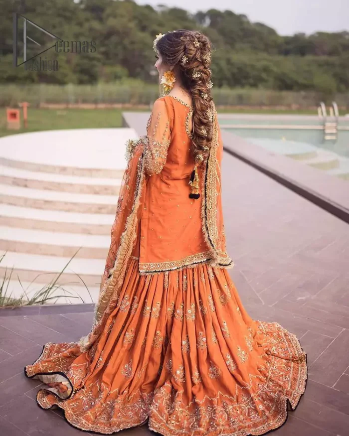 Time to treat yourself with an orange article of Deemas Fashion. This orange heartiest mealtime article will twirl your heart.  Prettify your Mehndi look with this orange short shirt that is embellished with tilla, kora and dabka work. Its rounded neckline with full sleeves gives you a genuine feeling of a bride. It is synchronized with flayer orange sharara that has an embellished border and spray of tiny floral motifs that gives a super aesthetic look to this dress. Finish this look with a net dupatta that has four sides embellished border and Kiran work.
