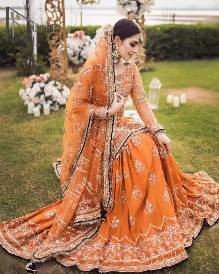 Time to treat yourself with an orange article of Deemas Fashion. This orange heartiest mealtime article will twirl your heart.  Prettify your Mehndi look with this orange short shirt that is embellished with tilla, kora and dabka work. Its rounded neckline with full sleeves gives you a genuine feeling of a bride. It is synchronized with flayer orange sharara that has an embellished border and spray of tiny floral motifs that gives a super aesthetic look to this dress. Finish this look with a net dupatta that has four sides embellished border and Kiran work.