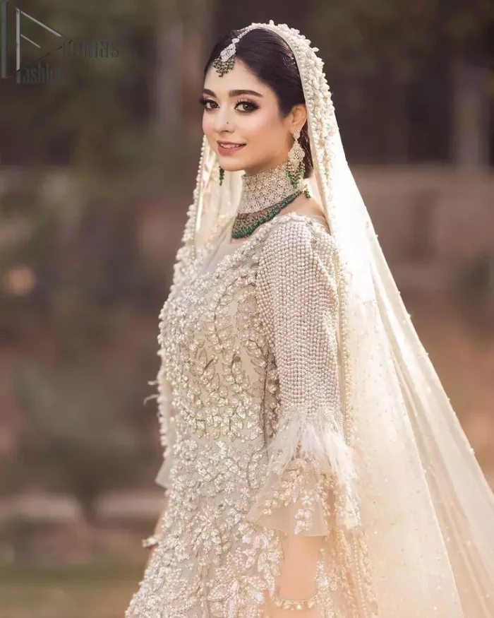 Nothing shines out more than a bride in her most natural state. For the Love of Ivory, this outfit was originally made in the shade of ivory to match the modern look in reception. This full sleeves ivory maxi is just decorated with 3D handsome flowers, style up with pearls embroidery and boat shape illusion neckline. Furthermore, the back train of this maxi gives you a super dazzling look on your reception day. Pair it up with the same colour dupatta made with pure net and embellished with a four-sided border to glamourous and enhance the combination.
