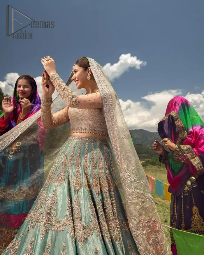 Talking about traditional, Deemas Fashion introduces the Aqua Lehenga and pink blouse which is an outstanding upgrade to bridal wear. This stunning full-sleeved attire presents an enchanting sweetheart neckline, embellished with the finest work of light golden embroidery, and adorned with pearls. This bridal wear has its own admiring look that comes with a tissue dupatta with embellished border. The Aqua colour of Lehenga gives so soothing look to the whole outfit. Furthermore, the lehenga is delicately adorned with golden kora, dabka, tilla, sequins and pearls embroidery. The border of the lehenga is also ornamented with embellished applique which gives the perfect ending to this outfit.