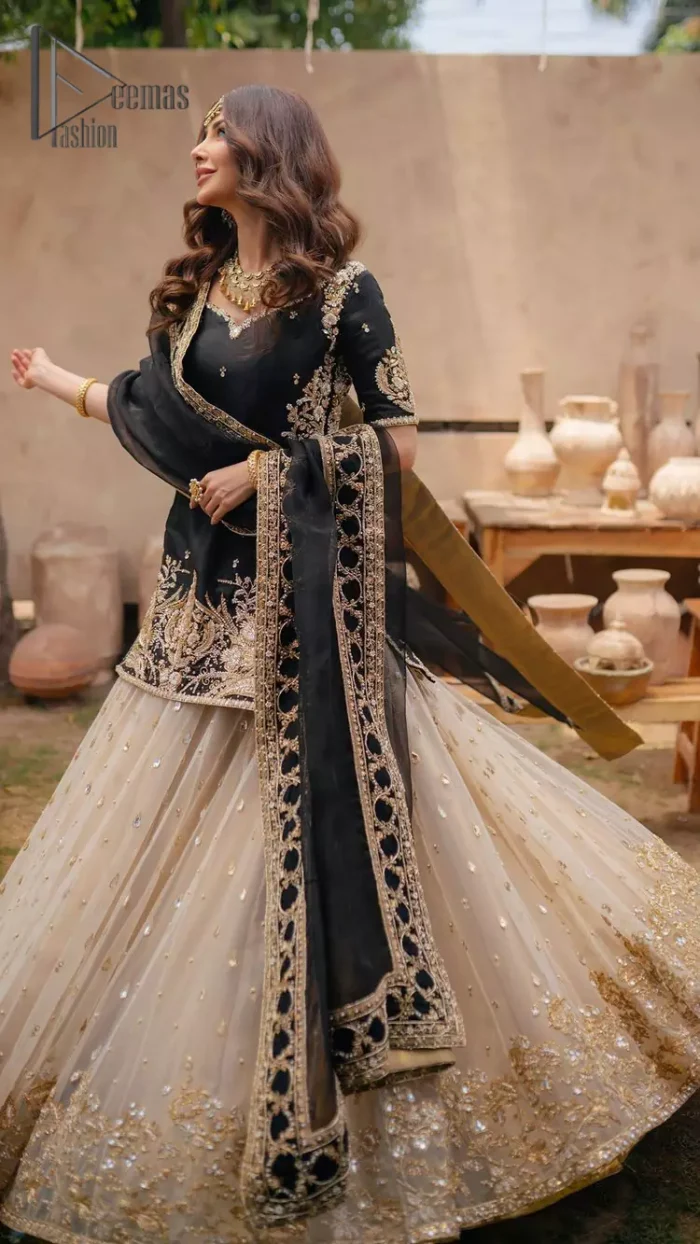 Do you want to feel like a superstar? So this stunning article is designed only for you. Just wear our black half sleeve short shirt embellished with kora, dabka and crystal work and fulfil your dream to feel like a superstar. Furthermore, It also comprises the beautiful, embellished border on the Daman. It is coordinated with a black net dupatta that is finished with geometric patterns on all four sides and comes with an Ivory can-can lehenga. The border of the lehenga is embellished with zardozi work giving a super aesthetic look to this artistic article.
