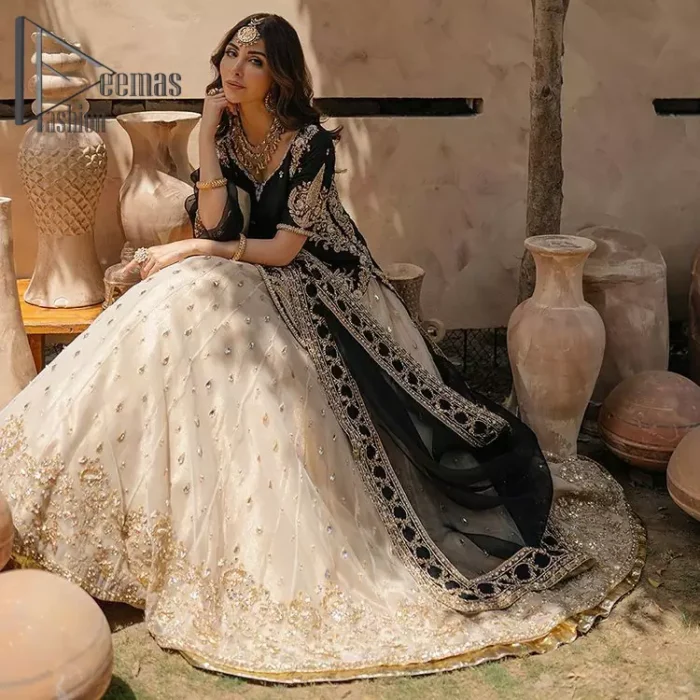 Do you want to feel like a superstar? So this stunning article is designed only for you. Just wear our black half sleeve short shirt embellished with kora, dabka and crystal work and fulfil your dream to feel like a superstar. Furthermore, It also comprises the beautiful, embellished border on the Daman. It is coordinated with a black net dupatta that is finished with geometric patterns on all four sides and comes with an Ivory can-can lehenga. The border of the lehenga is embellished with zardozi work giving a super aesthetic look to this artistic article.