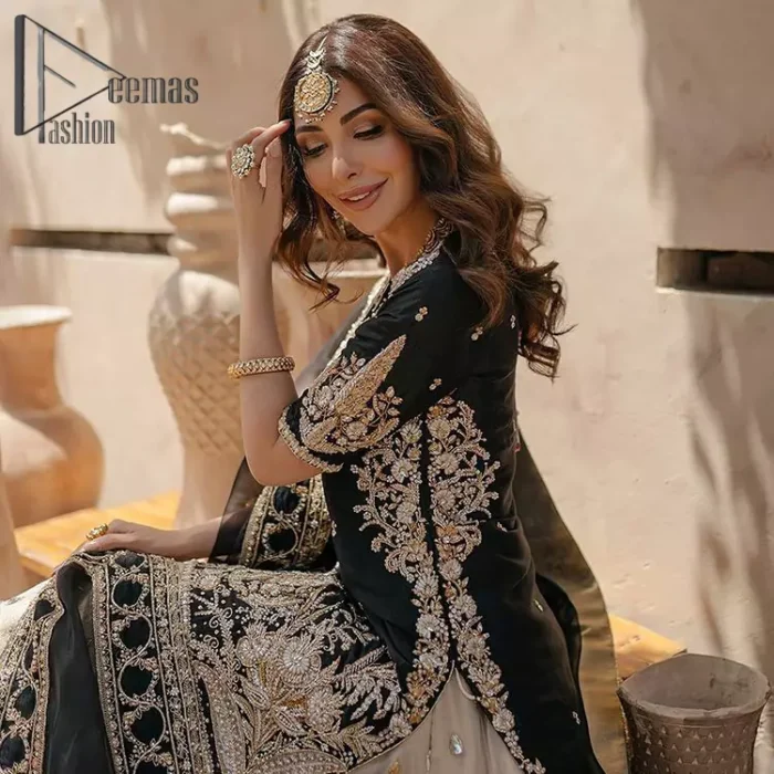 Do you want to feel like a superstar? So this stunning article is designed only for you. Just wear our black half sleeve short shirt embellished with kora, dabka and crystal work and fulfil your dream to feel like a superstar. Furthermore, It also comprises the beautiful, embellished border on the Daman. It is coordinated with a black net dupatta that is finished with geometric patterns on all four sides and comes with an Ivory can-can lehenga. The border of the lehenga is embellished with zardozi work giving a super aesthetic look to this artistic article.