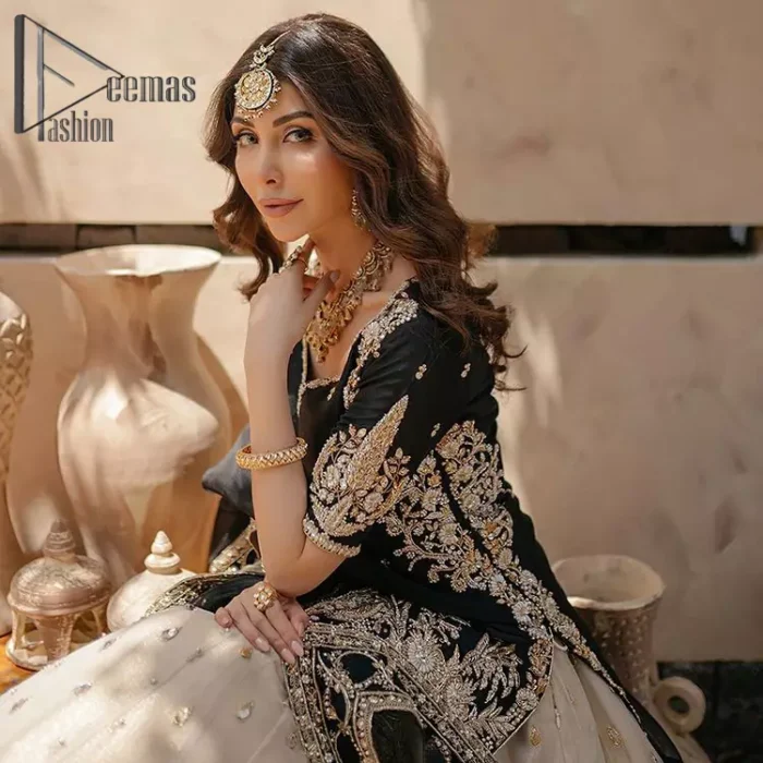 Do you want to feel like a superstar? So this stunning article is designed only for you. Just wear our black half sleeve short shirt embellished with kora, dabka and crystal work and fulfil your dream to feel like a superstar. Furthermore, It also comprises the beautiful, embellished border on the Daman. It is coordinated with a black net dupatta that is finished with geometric patterns on all four sides and comes with an Ivory can-can lehenga. The border of the lehenga is embellished with zardozi work giving a super aesthetic look to this artistic article.