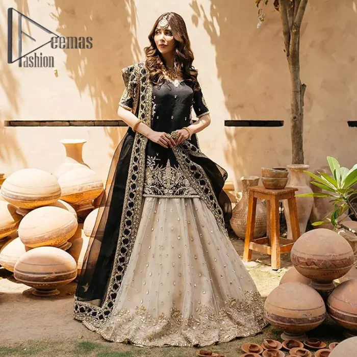 Do you want to feel like a superstar? So this stunning article is designed only for you. Just wear our black half sleeve short shirt embellished with kora, dabka and crystal work and fulfil your dream to feel like a superstar. Furthermore, It also comprises the beautiful, embellished border on the Daman. It is coordinated with a black net dupatta that is finished with geometric patterns on all four sides and comes with an Ivory can-can lehenga. The border of the lehenga is embellished with zardozi work giving a super aesthetic look to this artistic article.