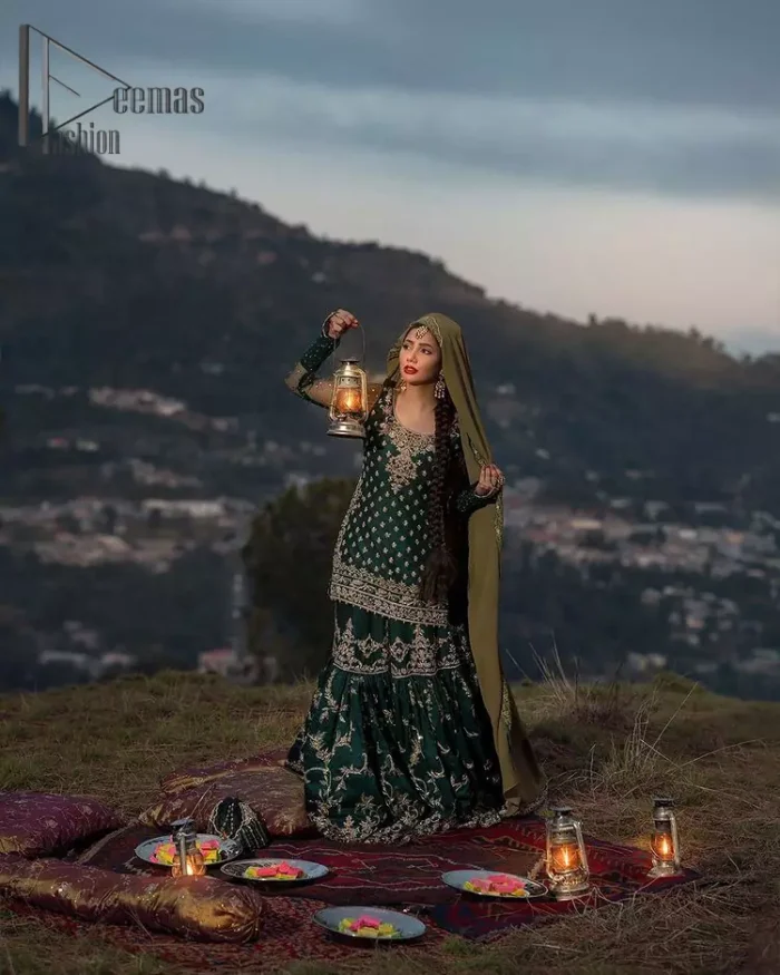 The eccentric Bottle Green outfit sings a melody just for you! The ghrara in bottle green is enriched with golden embroidery to create a modern vibe. This surprising full-sleeved shirt presents an outstanding sweetheart neckline, embellished with the finest work of golden and silver embroidery, and adorned with pearls while the details make it perfectly festive. Style it up with an organza dupatta which is sprinkled with sequins all over and four sides Kiran to give it a dreamy legal and royal look.