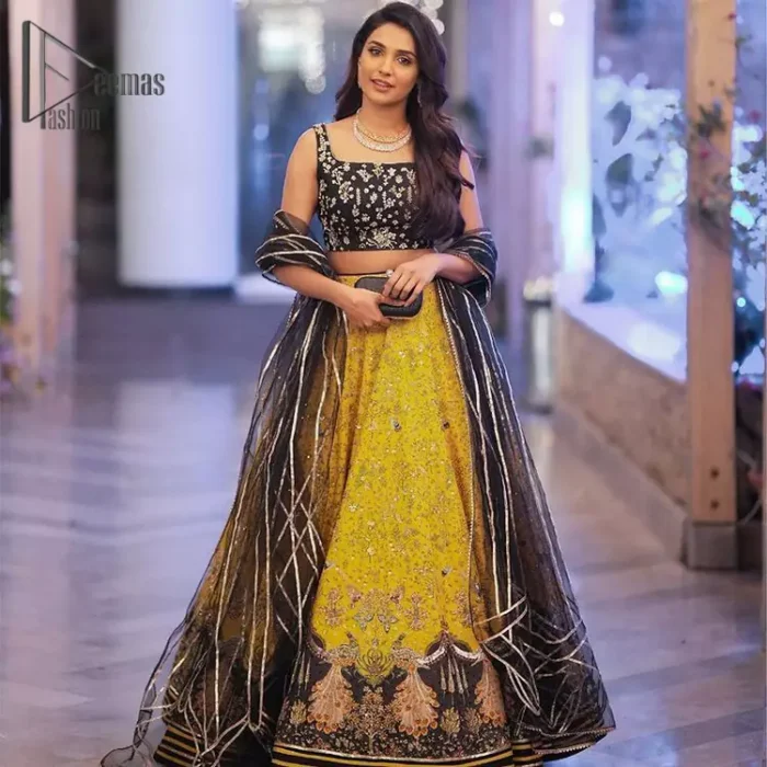 You smelled like sunshine and daisies when this pure magic wrapped around as our embroidery is luxurious. Yellow and black is the super trend of mehndi occasions. This eye-catching sleeveless black blouse having boat shape neckline looks priceless in silver and golden embroidery. In addition to this, yellow lehenga embellished with kora, dabka and sequins work and beautifully designed borders with zardozi, applique and Kiran shows the feeling of mehndi bride. Pair it up with a black dupatta that you would definitely want to wear for your next event.
