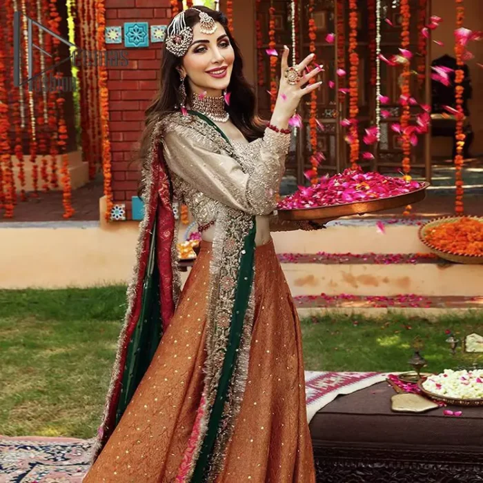 You have got plans for your mehndi? DeemasFashion got you to look!  Just go bold and bright with a beige blouse that is garnished with the same color thread embroidery and the blouse is highlighted with a square neckline and full sleeves. Further, the bottom of the blouse is adorned with red pearls that grant you a brilliant look. It is paired up with an orange lehenga that border is attractively enriched with golden embroidery and sequins spray all over. Finish this look with a green dupatta that is sprinkled with a four-sided Kiran and four sider border as well.