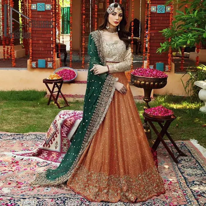 You have got plans for your mehndi? DeemasFashion got you to look!  Just go bold and bright with a beige blouse that is garnished with the same color thread embroidery and the blouse is highlighted with a square neckline and full sleeves. Further, the bottom of the blouse is adorned with red pearls that grant you a brilliant look. It is paired up with an orange lehenga that border is attractively enriched with golden embroidery and sequins spray all over. Finish this look with a green dupatta that is sprinkled with a four-sided Kiran and four sider border as well.