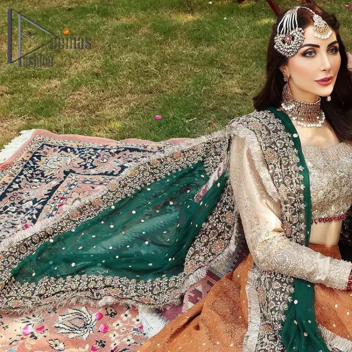 You have got plans for your mehndi? DeemasFashion got you to look!  Just go bold and bright with a beige blouse that is garnished with the same color thread embroidery and the blouse is highlighted with a square neckline and full sleeves. Further, the bottom of the blouse is adorned with red pearls that grant you a brilliant look. It is paired up with an orange lehenga that border is attractively enriched with golden embroidery and sequins spray all over. Finish this look with a green dupatta that is sprinkled with a four-sided Kiran and four sider border as well.