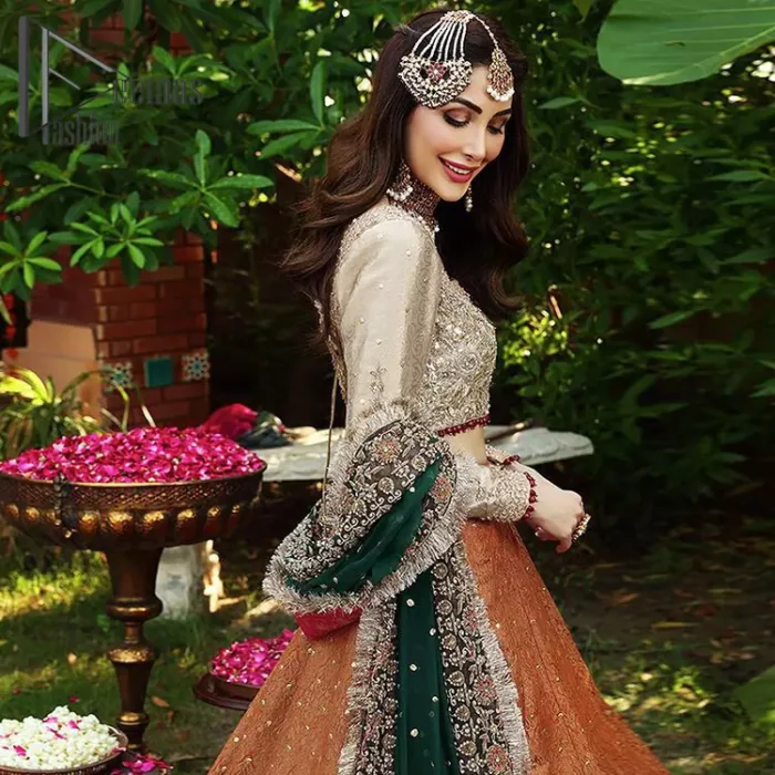You have got plans for your mehndi? DeemasFashion got you to look!  Just go bold and bright with a beige blouse that is garnished with the same color thread embroidery and the blouse is highlighted with a square neckline and full sleeves. Further, the bottom of the blouse is adorned with red pearls that grant you a brilliant look. It is paired up with an orange lehenga that border is attractively enriched with golden embroidery and sequins spray all over. Finish this look with a green dupatta that is sprinkled with a four-sided Kiran and four sider border as well.
