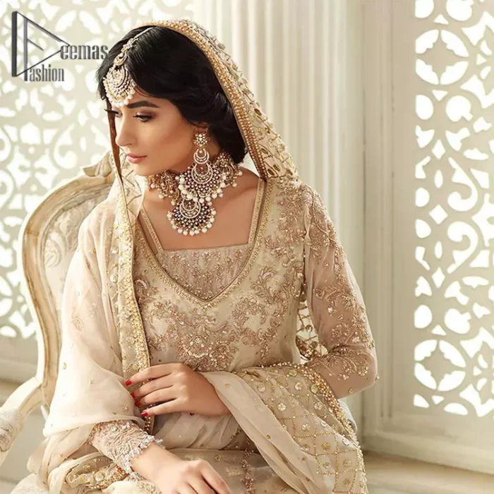 Pure bliss is seeing a bride smiling ear to ear through her whole wedding. Just go with a retro vibe on your Nikkah, everyone calls you super queen. This ivory long shirt is pleasingly furnished with golden and antique embroidery that includes kora, dabka, tilla, and crystal work. The inner blouse is intensified with a square neckline just to give you a super surprising look. It is systemized with ivory sharara that border is embellished with beautiful embroidery as well. Complete this amazing look with a dupatta which is adorned with a four-sided handsome border and sequins spray all over with so much love.