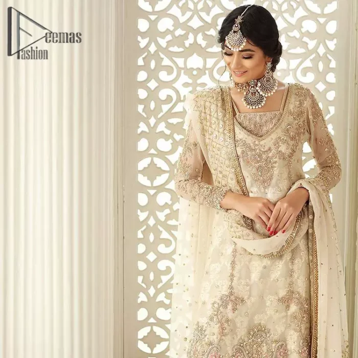 Pure bliss is seeing a bride smiling ear to ear through her whole wedding. Just go with a retro vibe on your Nikkah, everyone calls you super queen. This ivory long shirt is pleasingly furnished with golden and antique embroidery that includes kora, dabka, tilla, and crystal work. The inner blouse is intensified with a square neckline just to give you a super surprising look. It is systemized with ivory sharara that border is embellished with beautiful embroidery as well. Complete this amazing look with a dupatta which is adorned with a four-sided handsome border and sequins spray all over with so much love.