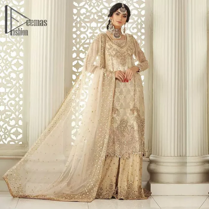 Pure bliss is seeing a bride smiling ear to ear through her whole wedding. Just go with a retro vibe on your Nikkah, everyone calls you super queen. This ivory long shirt is pleasingly furnished with golden and antique embroidery that includes kora, dabka, tilla, and crystal work. The inner blouse is intensified with a square neckline just to give you a super surprising look. It is systemized with ivory sharara that border is embellished with beautiful embroidery as well. Complete this amazing look with a dupatta which is adorned with a four-sided handsome border and sequins spray all over with so much love.