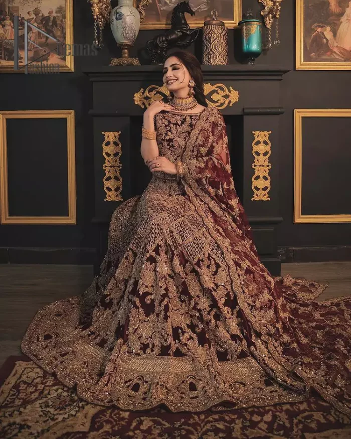 With the right outfit, every bride can rule the world! As nothing makes a bride more beautiful than the trust of her outfit. Introducing maroon half sleeves blouse that is fully embellished with tilla, kora and dabka work. In addition to this, the boat shape neckline of this blouse that is made with pure velvet gives you a dreamy look. It is synchronized with a velvet lehenga that is adorned with priceless heavy embroidery. Finish this look with an organza dupatta, embellished with embroidered scalloped borders to give you a relaxing and soothing look on your reception.