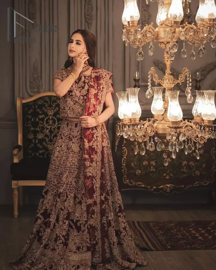 With the right outfit, every bride can rule the world! As nothing makes a bride more beautiful than the trust of her outfit. Introducing maroon half sleeves blouse that is fully embellished with tilla, kora and dabka work. In addition to this, the boat shape neckline of this blouse that is made with pure velvet gives you a dreamy look. It is synchronized with a velvet lehenga that is adorned with priceless heavy embroidery. Finish this look with an organza dupatta, embellished with embroidered scalloped borders to give you a relaxing and soothing look on your reception.