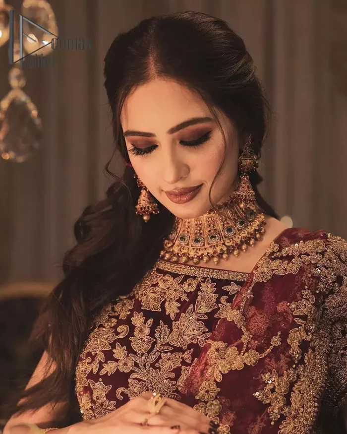 With the right outfit, every bride can rule the world! As nothing makes a bride more beautiful than the trust of her outfit. Introducing maroon half sleeves blouse that is fully embellished with tilla, kora and dabka work. In addition to this, the boat shape neckline of this blouse that is made with pure velvet gives you a dreamy look. It is synchronized with a velvet lehenga that is adorned with priceless heavy embroidery. Finish this look with an organza dupatta, embellished with embroidered scalloped borders to give you a relaxing and soothing look on your reception.